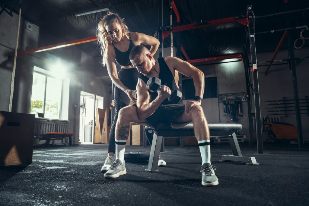 Hombre y mujer atléticos con pesas entrenando y practicando en el gimnasio. Concepto de deporte, estilo de vida saludable, bienestar. Gy Picacho Ajusco